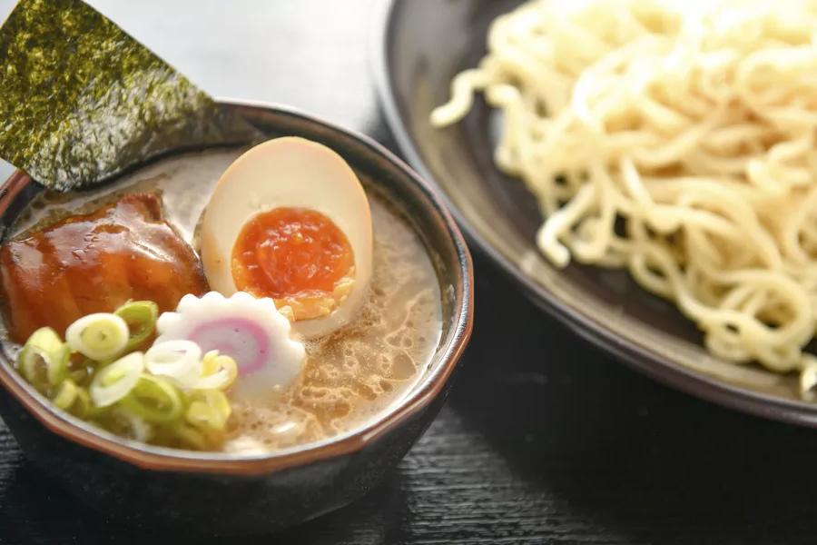 Close-up de uma tigela de macarrão e uma tigela de sopa de ramen 和 um ovo escalfado, 切成两半.