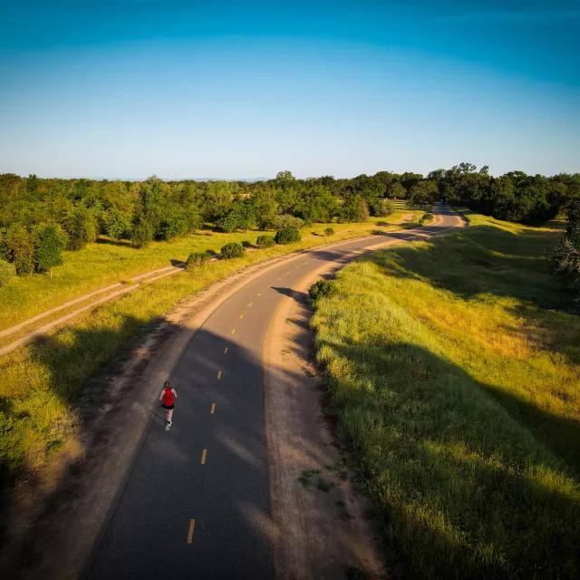 Overhead shot of woman running on a road through the countryside